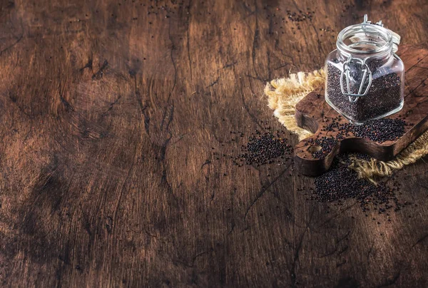 ガラスの瓶 ビンテージ キッチン テーブル背景 セレクティブ フォーカスから注がれる黒いキノア種子 — ストック写真