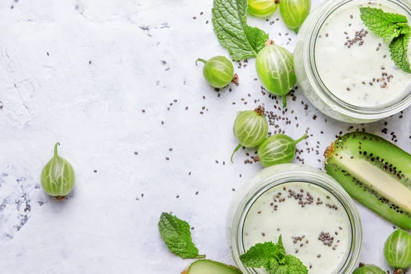 Bektaşi üzümünden meyve suyu ve milkshake, kivi ve yoğurtlu süt kokteyli? Chia tohumları, gri mutfak masası arka planı, düz yatak, üst görünüm