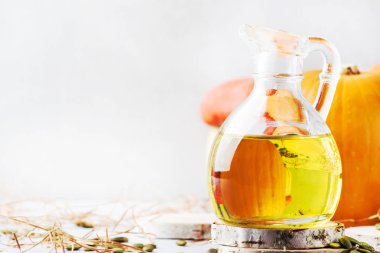 Cam sürahi beyaz rustik arka planda - şifa ve sağlıklı gıda kavramı, seçici odak ışık petrol Kabak tohumları