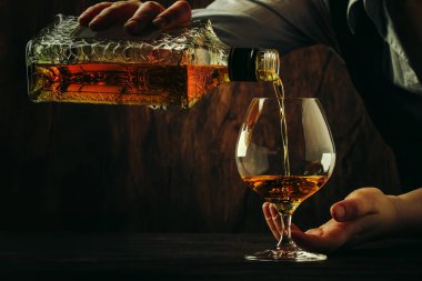 Barmen büyük şarap cam eski konyak veya brendi dökülen bar sayacı. Antika ahşap arka plan pub veya bar, gece ruh hali. Tonlama, seçici odak metin için yer