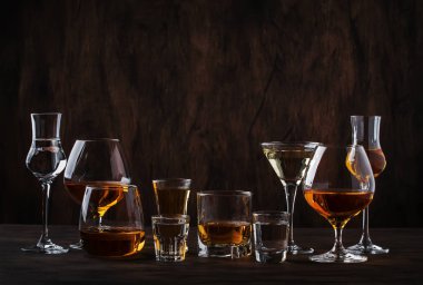 Seçim zor güçlü alkollü içecekler büyük gözlük ve küçük shot cam assortent: votka, konyak, tekila, brendi ve viski, grappa, likör, vermut, tentür, ROM. Vintage counter arka plan, seçici odak, kopya alanı ahşap