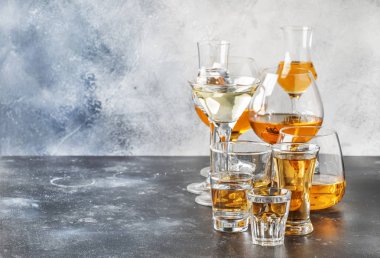 Seçim zor güçlü alkollü içecekler büyük gözlük ve küçük shot cam assortent: votka, konyak, tekila, brendi ve viski, grappa, likör, vermut, tentür, ROM. Gri bar counter arka plan, seçici odak, kopya alanı