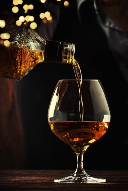 Barmen büyük şarap cam eski konyak veya brendi dökülen bar sayacı. Antika ahşap arka plan pub veya bar, gece ruh hali. Tonlama, seçici odak metin için yer