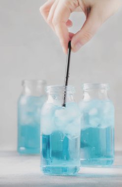 El saman içki koyar. Spor ve fitness içki kavramı, soğuk izotonik mavi su şişeleri, gri tablo arka plan, seçici odak