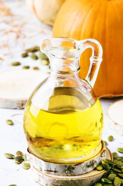 Cam sürahi beyaz rustik arka planda - şifa ve sağlıklı gıda kavramı, seçici odak ışık petrol Kabak tohumları