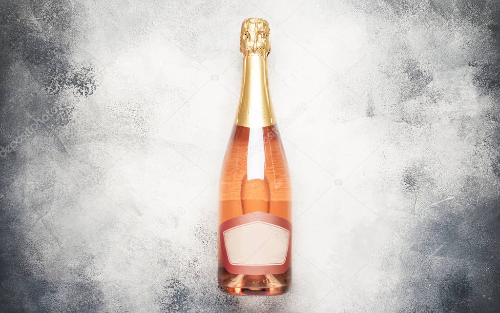 Bottle with pink sparkling wine or rose champagne and glasses, gray background with place for text, holiday or date concept, flat lay, top view