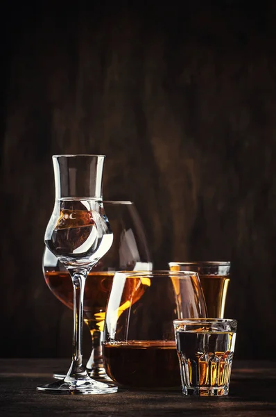 ハードの強いアルコールの選択の飲み物を Assortent で大きなメガネとショット グラス ウォッカ コニャック テキーラ ブランデー ウィスキー グラッパ — ストック写真