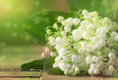 Antika ahşap masa, seçici odak beyaz kokulu zambaklar vadideki yaprakları ile buket bahar