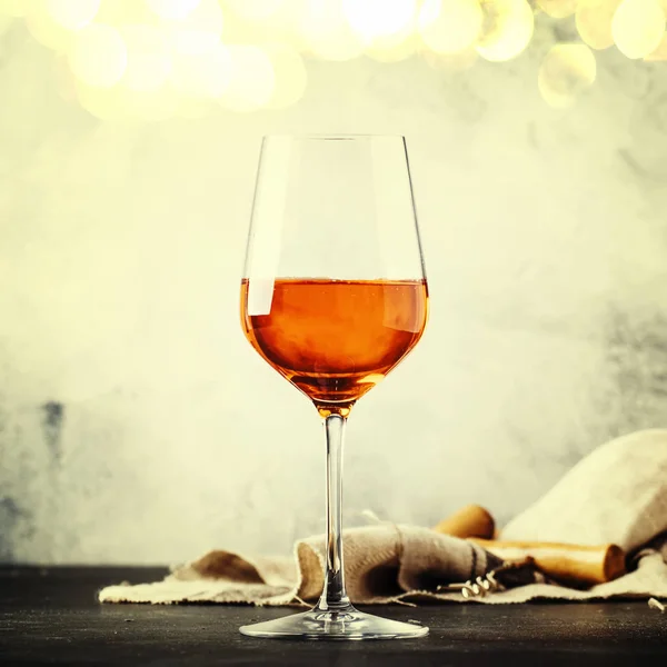 Trendy food and drink, orange wine in glass, gray table background, space for text, selective focus. Square image, vintage toning
