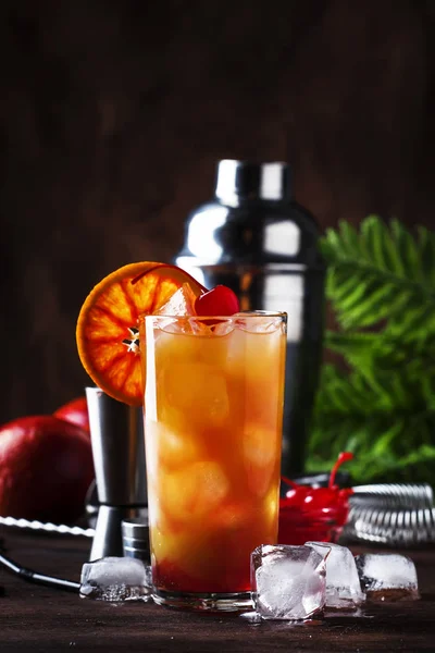 Summer tequila sunrise cocktail with silver tequila, grenadine syrup, orange and ice cubes. Wooden bar counter in the beach bar. Selective focus. Place for text