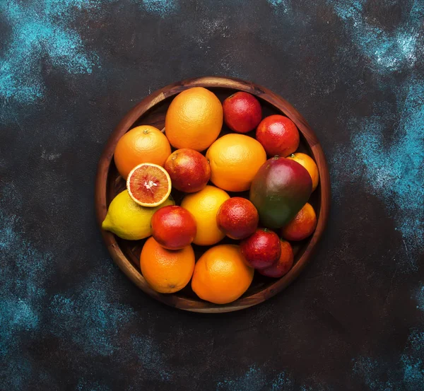 Bright fruits in large tray: oranges, lemons, mango in assortment. View from above