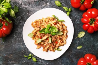 Beyaz tabak, koyu arka plan mutfak masası, üstten görünüm yeşil fesleğen ile kıyılmış et ve domates soslu lezzetli makarna