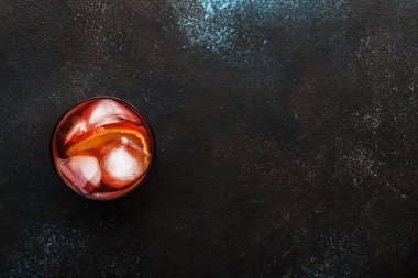 Kuru cin, kırmızı vermut ve kırmızı acı, portakal ve buz küpleri ile trendy alkollü kokteyl Negroni. Brown bar counter arka plan, minimalist tarzı, üstten görünüm, metin için yer.