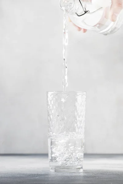 Acqua Limpida Viene Versata Dalla Bottiglia Vetro Vetro Sfondo Grigio — Foto Stock