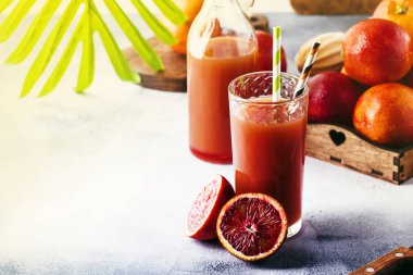 Yaz meyve suyu veya alkolsüz serinletici sağlıklı kokteyl veya taze sıkılmış kırmızı Sicilya portakal, parlak ışık masa artalanını içki. Seçici odak