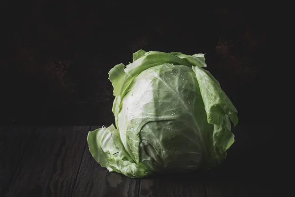 Big head of fresh cabbage, spring harvest, on dark rustic background, selective focus, minimalism, low key