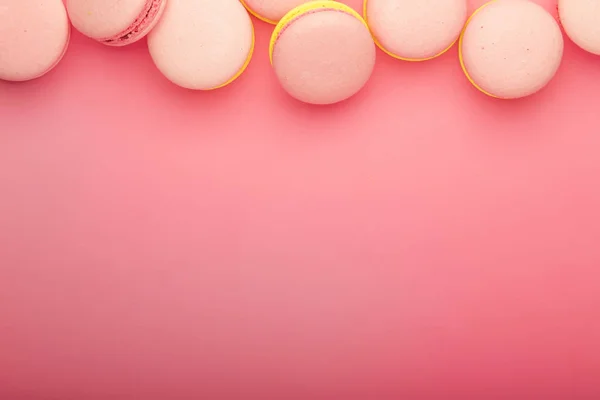 Pink yellow macaroons on soft pink background table, place for text, minimalism style, top view