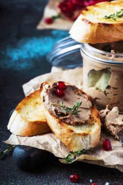 Lezzetli tavuk karaciğer pate nar taneleri ve kekik, karanlık mutfak arka plandaki tabloda, metin, seçici odak için yer ile kızarmış ekmek üzerinde