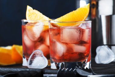 Yaz kuru cin, kırmızı vermut ve kırmızı acı, portakal dilimi ve buz küpleri ile alkollü kokteyl Negroni. Brown bar counter arka plan, araçları, metin, seçici odak için yer