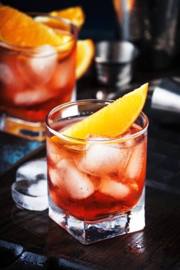 Yaz kuru cin, kırmızı vermut ve kırmızı acı, portakal dilimi ve buz küpleri ile alkollü kokteyl Negroni. Brown bar counter arka plan, araçları, metin, seçici odak için yer