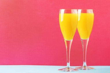Festival alkol kokteyl Mimoza portakal suyu ve soğuk kuru şampanya ve köpüklü şarap gözlük, pembe treandy arka plan, metin, seçici odak için yer