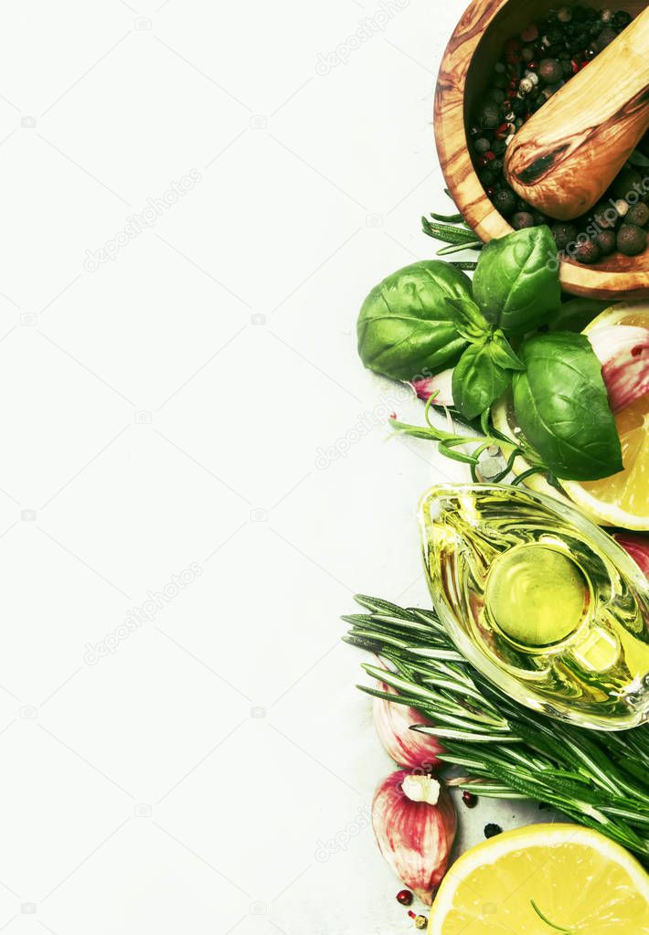 Spice mix, fresh spicy herbs: rosemary, green basil, red garlic, assorted pepper, olive oil on gray kitchen table, food cooking background, top view