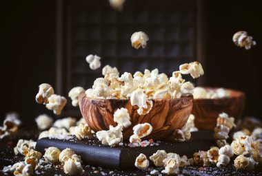 Salted popcorn in a wooden bowl, unhealthy food, dark wooden kitchen table background, selective focus clipart