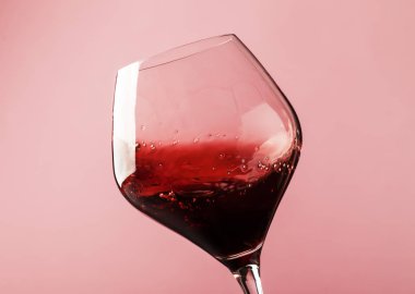 Dry red wine, splash in glass, pink background, defocused in motion image, shallow depth of field clipart