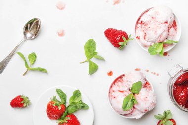 Çilekli dondurma reçel tepesi ile dekore edilmiş yeşil nane yaprakları, gri mutfak masa artalanını, üstten görünüm