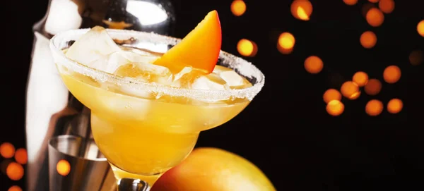 Mango daiquiri, alcoholic cocktail with white rum, liqueur, syrup, lemon juice, mango and ice on black bar counter background, copy space, selective focus