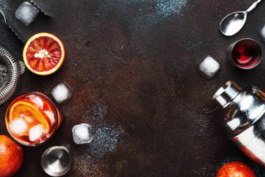 Trendy iç, Kuru cin, kırmızı vermut ve kırmızı acı, portakal dilimi ve buz küpleri ile alkollü kokteyl Negroni. Brown bar counter arka plan, araçlar, üstten görünüm, yaz ruh kavramı, kopya alanı bar