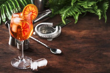 Portakal dilimleri, yaz soğuk taze alkollü soğuk içecek ile büyük şarap cam Aperol Spritz kokteyl. Araçlar ile ahşap bar karşı arka plan, palmiye yaprakları ile yaz ruh kavramı, kopya alanı, seçici odak