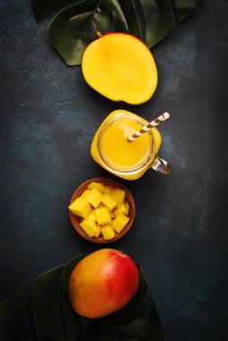 Taze sıkılmış taze mango suyu taze meyve ile büyük cam üzerinde koyu mavi arka plan, metin, en iyi görünüm için yer