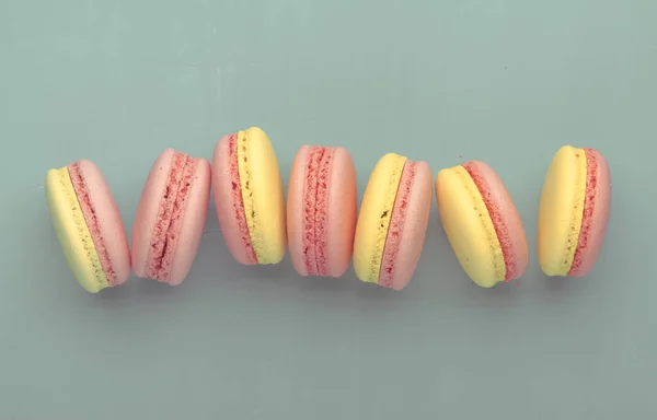 Pink yellow macaroons on blue graphic background, neon color, place for text, creative layout, top view