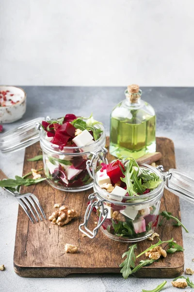 Beet salad with arugula, goat cheese and nuts, trendy salad jar, gray kitchen table background, selective focus