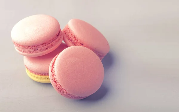 Pink yellow macaroons cakes on gray blue table background, place for text, trendy minimalism style, selective focus