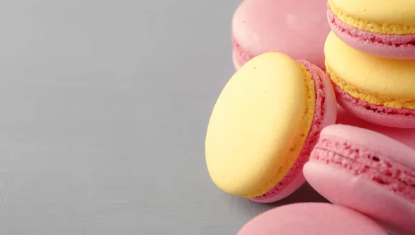 Pink yellow macaroons cakes on gray blue table background, place for text, trendy minimalism style, selective focus