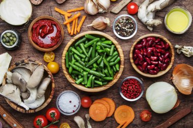 Yemek pişirme geçmişi, vejetaryen yemekleri, yeşil fasulye, sebze, kök, baharat, mantar ve bitkiler. Sağlıklı vejetaryen gıda konsepti. Rustik ahşap tablo, üst görünüm, kopyalama alanı