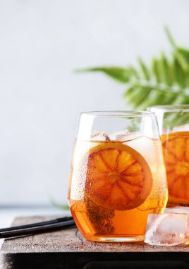 Köpüklü şarap, likör, buz ve Sicilya portakalı içeren bardakta Aperol spreyi kokteyli. Yaz alkolü içeceği. Aletleri olan gri bar tezgahı.