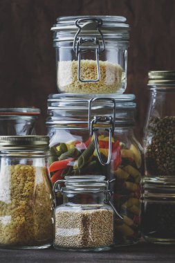 Yemek seti. Çiğ tahıllar, makarna, groats, organik baklagiller ve cam kavanoz yararlı tohumlar. Vegan protein ve enerji kaynakları kaynağıdır. Rustik ahşap mutfak masası arka plan. 