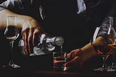 Barmen eski üzerinde küçük bardak içinde votka veya tekila dökülen bar sayacı. Antika ahşap arka plan pub veya bar, gece ruh hali. Tonlama, seçici odak metin için yer