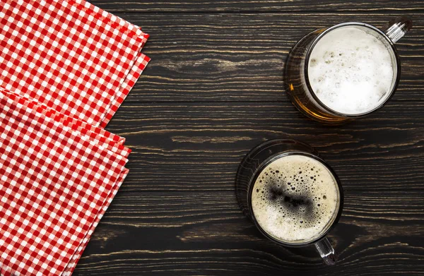 マグカップや塩味の軽食やナッツ 暗い木製のテーブル コピースペースのあるフレーム トップビューの光と暗いビール — ストック写真