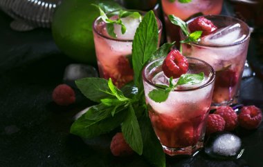 Alkollü kokteyl ahududu mojito berry, kireç, şurup, soda, rom, nane ve ezilmiş buz ile. Çelik çubuk takımları, siyah bar sayacı, seçici odak