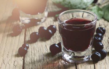 Eski ahşap masada taze çilek ile ev yapımı aronia likör, seçici odak