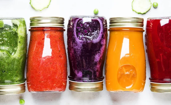 Food and drink background. Colorful vegan vegetable juices and smoothies set in bottles on white, top view