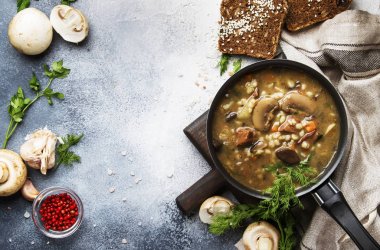 Sığır eti ve kepekli arpa ile sıcak etli sebze mantar çorbası. Siyah ekmek ile, metal tavada, üst görünüm, gri mutfak masası, kopya alanı