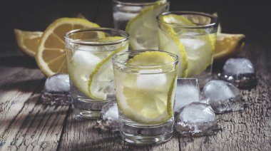 Limon dilimi ve shot cam buz ile Limon votka, vintage ahşap masa, seçici odak