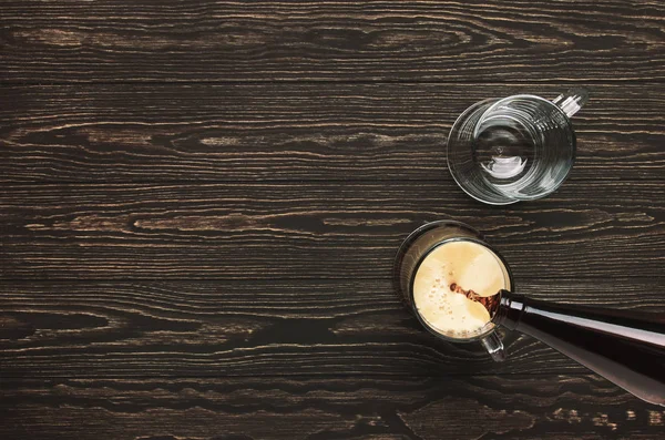 Dark beer, ale or stout is poured into glass, dark wooden bar counter, space for text, top view