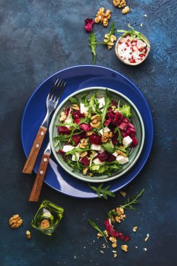 Arugula ile pancar yaz salatası, radicchio, çatal ile plaka üzerinde yumuşak peynir ve ceviz, mavi mutfak masasında sos ve baharatlar, kopya alanı, üst görünümü