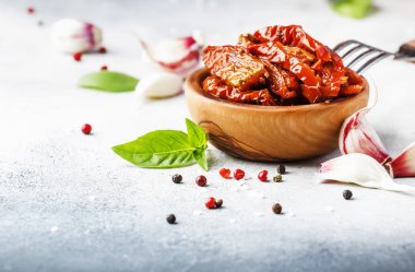 Gri mutfak masasında ahşap kase yeşil fesleğen ve baharat ile zeytinyağında kurutulmuş domates, metin için yer